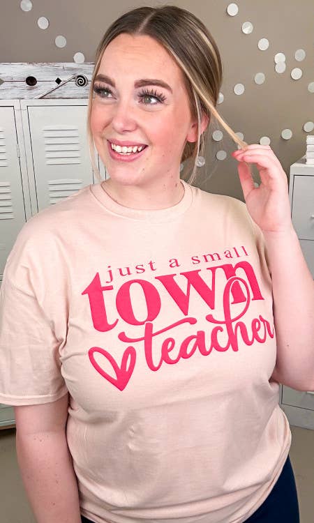 Person wearing a beige t-shirt with pink text in a casual setting