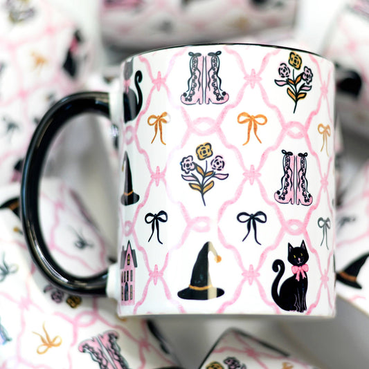 Mug with black cat, witch hat, and floral pattern on a pink background